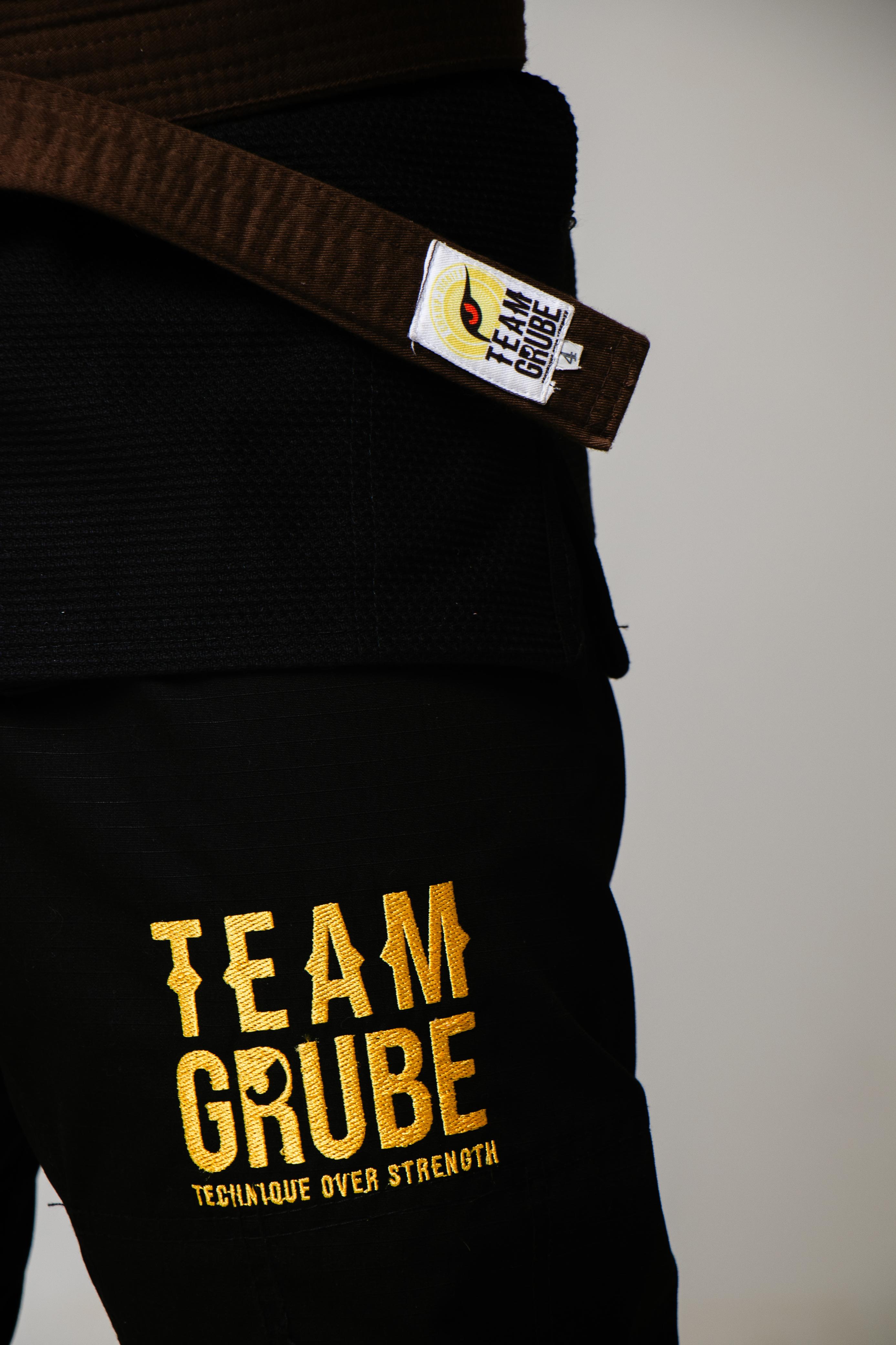 Detalhe do bordado dourado Team Grube na coxa da calça